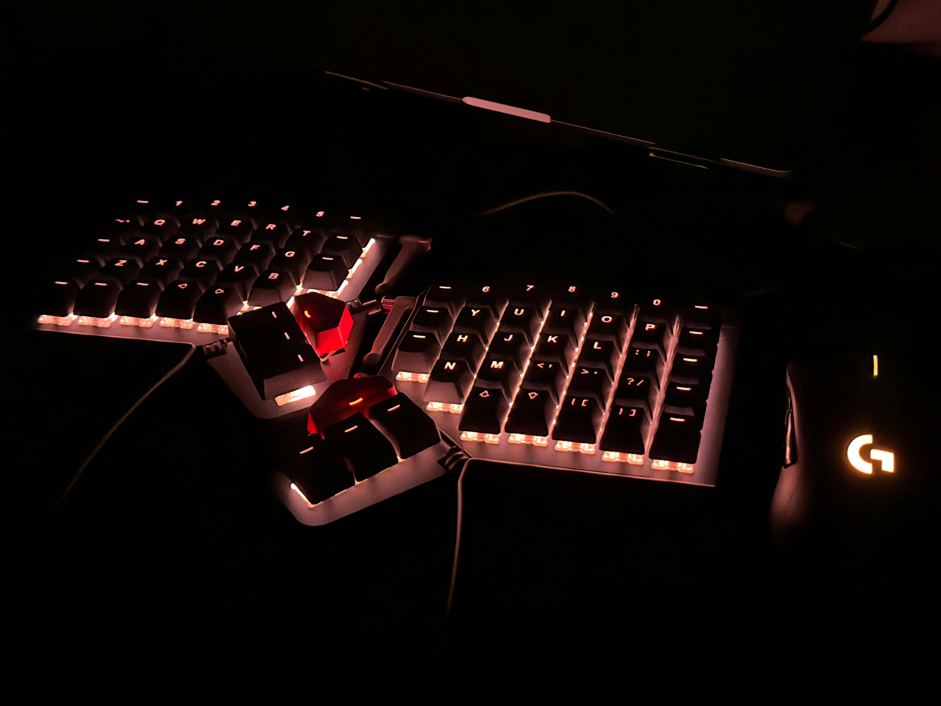 Keyboard and mouse in the dark, both with LED lights shining in an orange color that matches the Vesper theme's orange